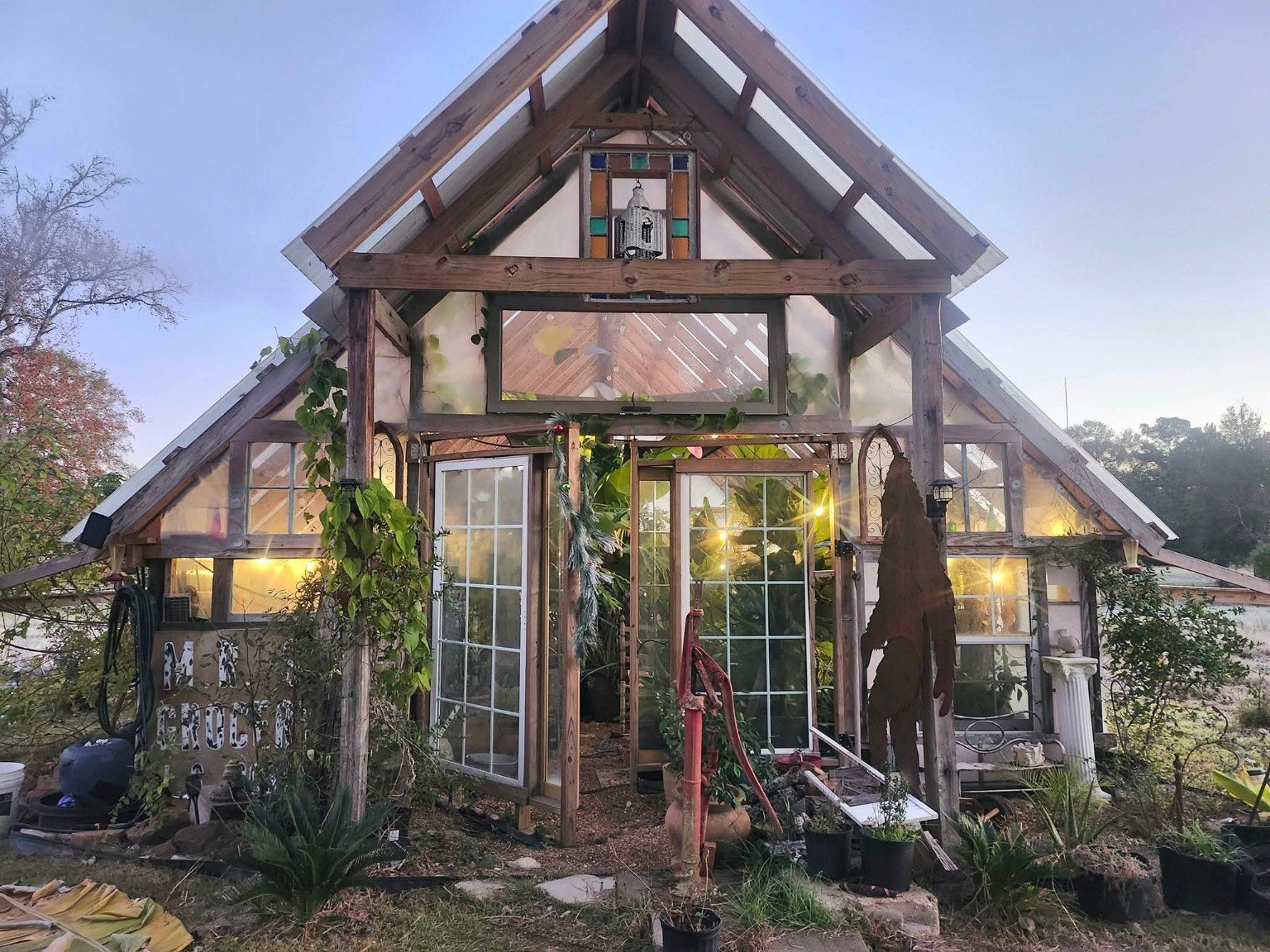 The greenhouse front at dusk with warm lights in the windows