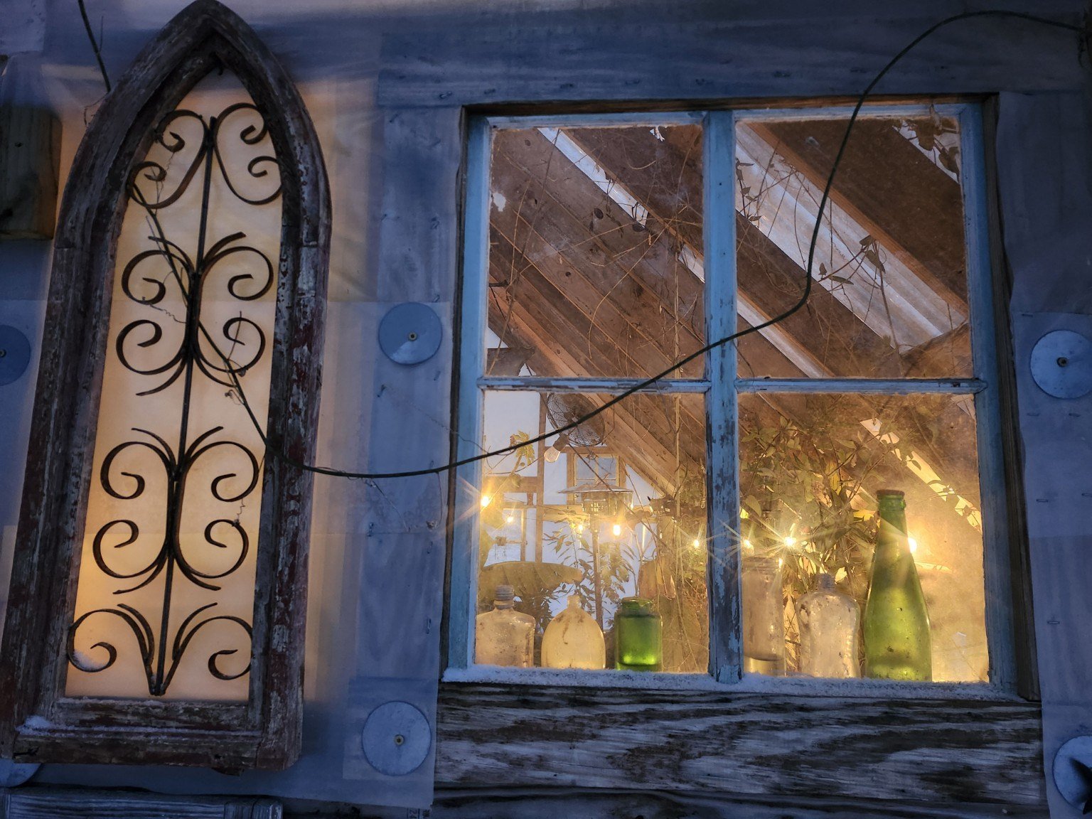 Warm light through reclaimed windows and arched ironwork